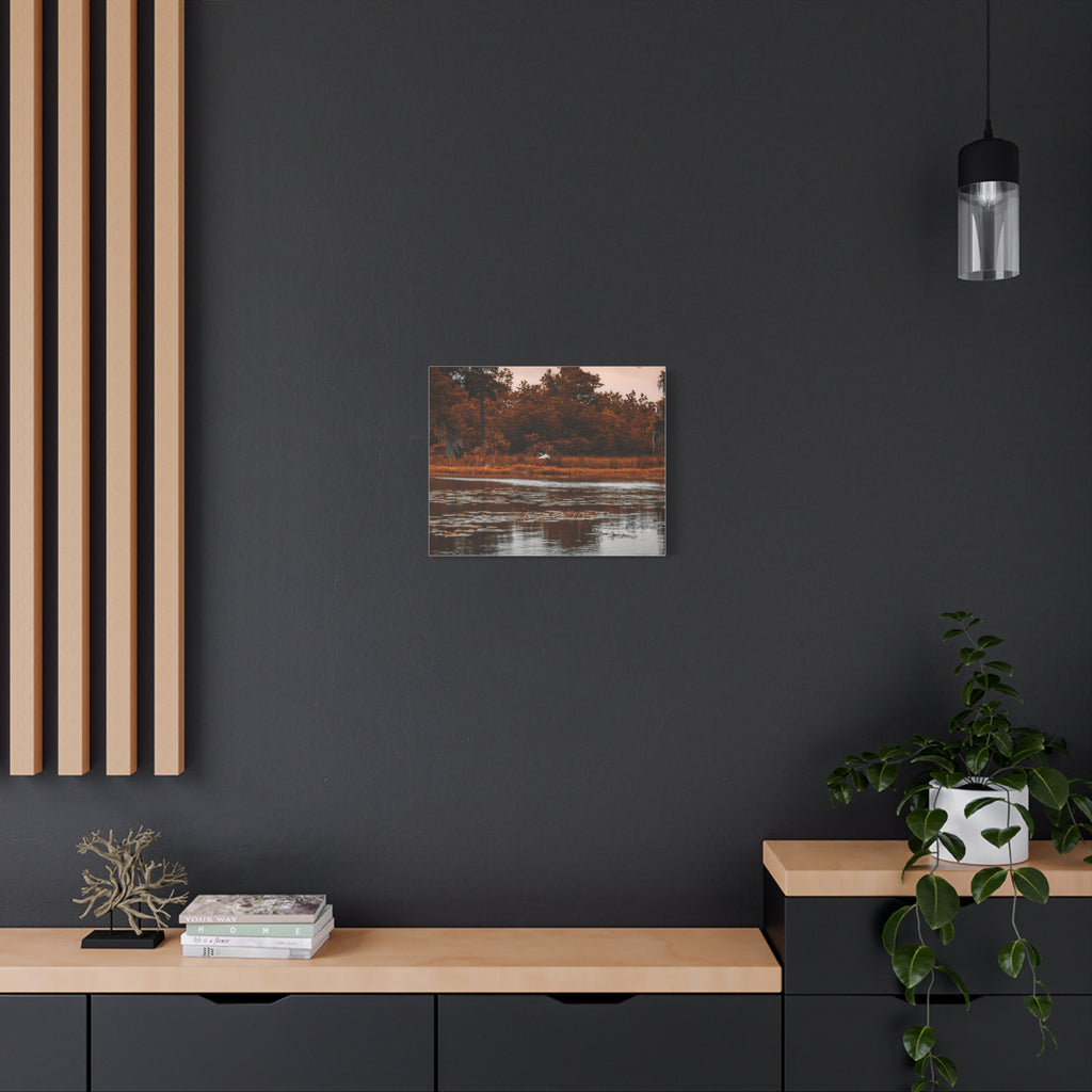 Heron in Amber Light canvas wall art displayed in a dark moody interior above a console table.